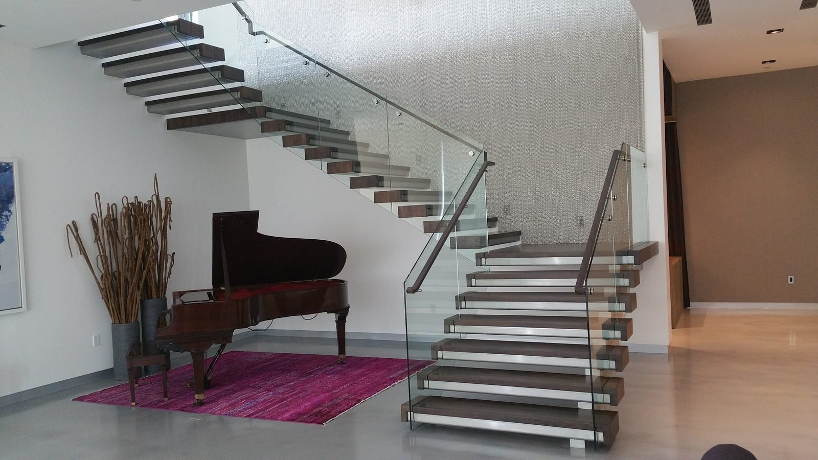 A custom floating wood staircase built by JD Stairs, with a grand piano in the foreground